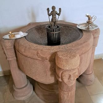 Taufbecken aus Stein mit bereitgestellten Taufutensilien